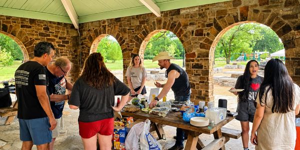 Group enjoying a picnic under a stone pavilion.