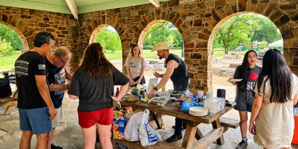 Friends gathering for a picnic under a stone pavilion.