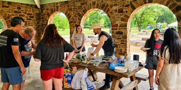 Group enjoying a picnic under stone arches at a park.