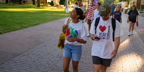 Two young people walking outdoors on a sunny day.