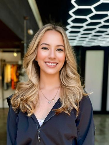 Smiling young woman with blonde hair in a modern indoor setting.
