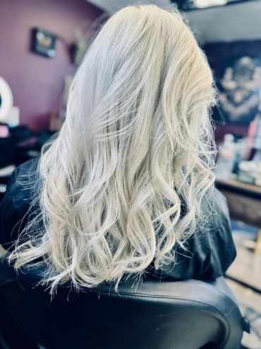 Long, wavy platinum blonde hair styled beautifully at a salon.