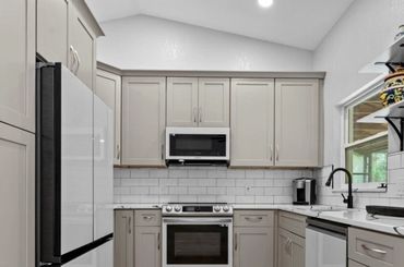 Modern kitchen with gray cabinets and white appliances.