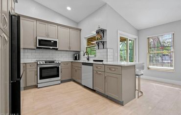 Modern kitchen with beige cabinets, white countertops, and stainless steel appliances.
