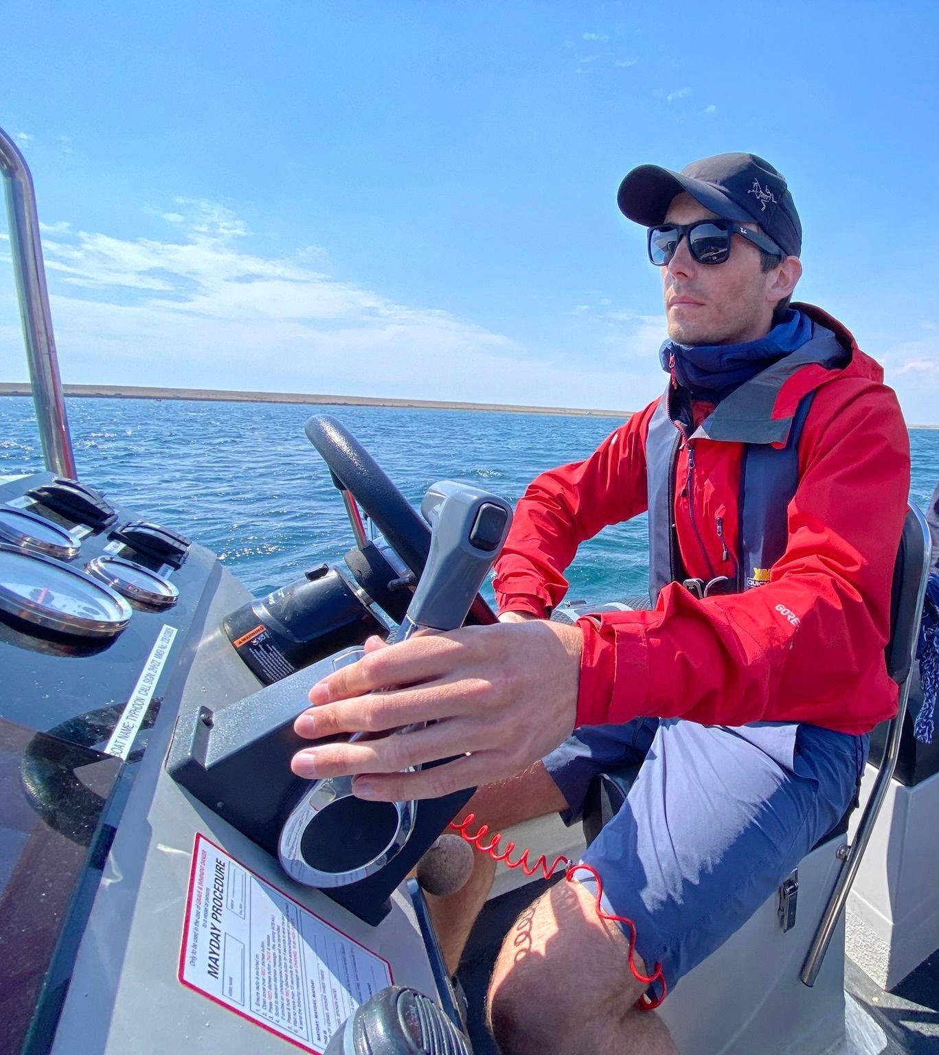 Man steering a boat on a sunny day.
