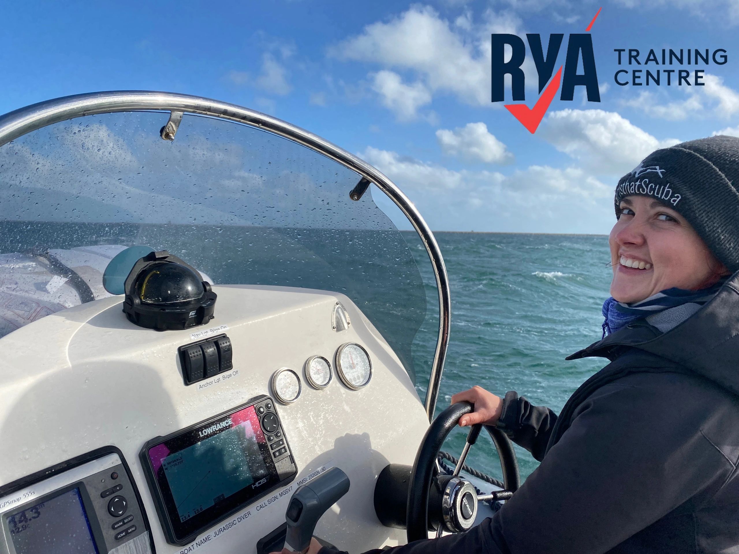 Smiling woman steering a boat with RYA Training Centre logo in the sky.