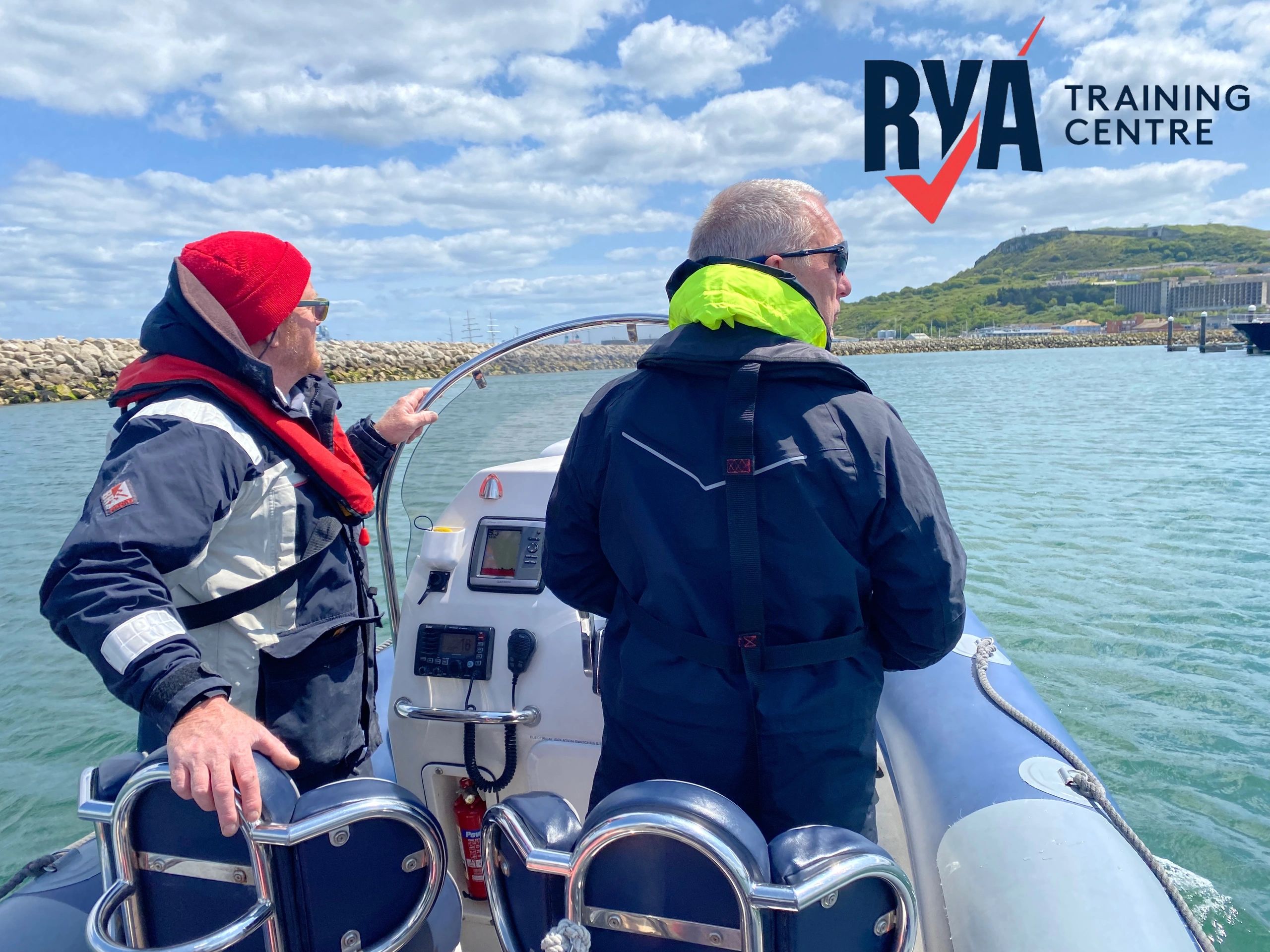 Two men boating near the shore with RYA Training Centre logo.