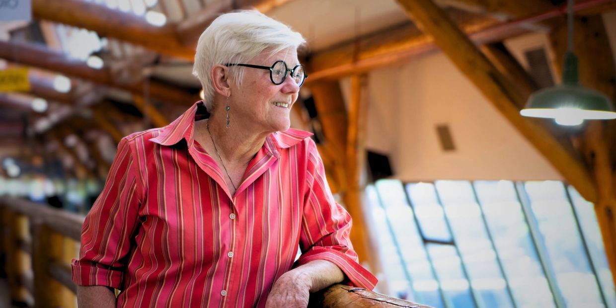 Elderly woman in red striped shirt smiling indoors.