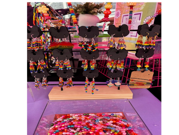 Colorful rainbow-themed earrings and jewelry displayed at a market stall.