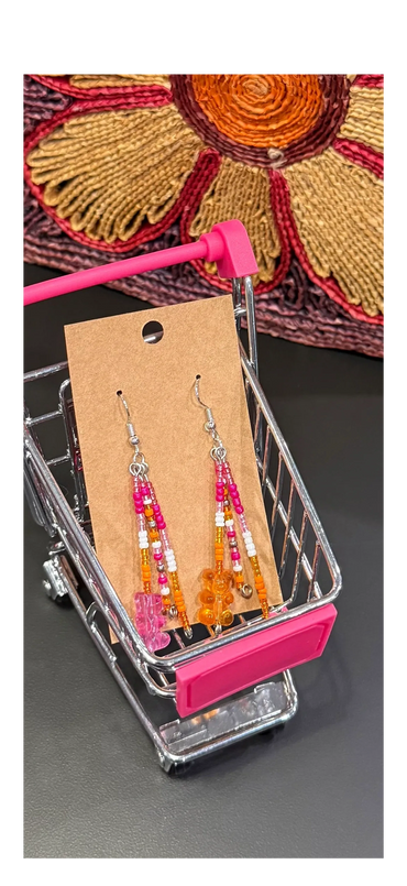 Colorful beaded earrings displayed in a miniature shopping cart.