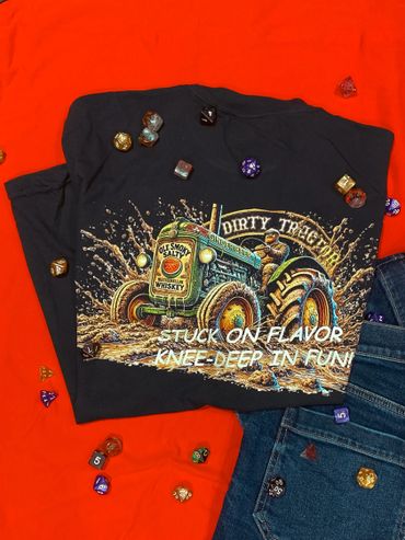 Graphic tee with a muddy tractor and gaming dice scattered around.