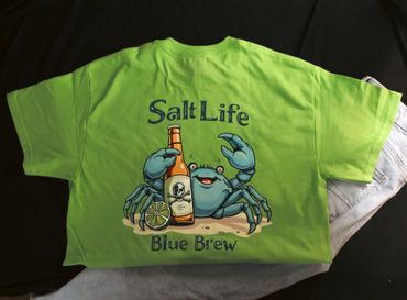 Bright green t-shirt featuring a blue crab holding a beer bottle with lime, labeled 'Salt Life Blue Brew'.