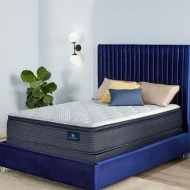 Elegant blue velvet bed with a plush mattress and decorative pillows in a minimalist bedroom.