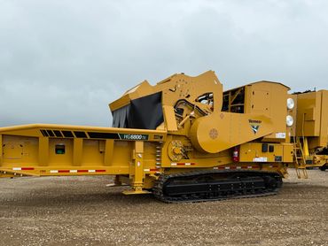 Yellow Vermeer HG6800TX industrial machine on dirt ground under cloudy sky.