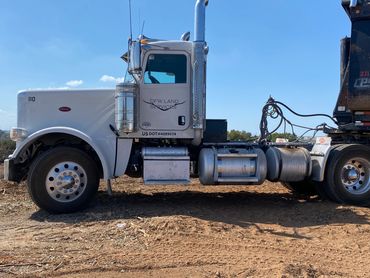 White Peterbilt truck with DFW Land Services logo parked on dirt.
