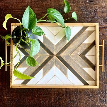 Geometric wood design on a table tray in greys and white with brushed brass handles.