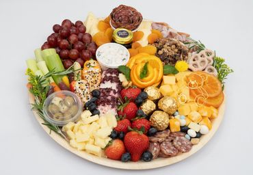 Colorful charcuterie board with fruits, cheeses, meats, and dips.