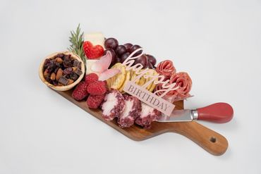 Birthday-themed charcuterie board with fruits, cheese, and crackers.