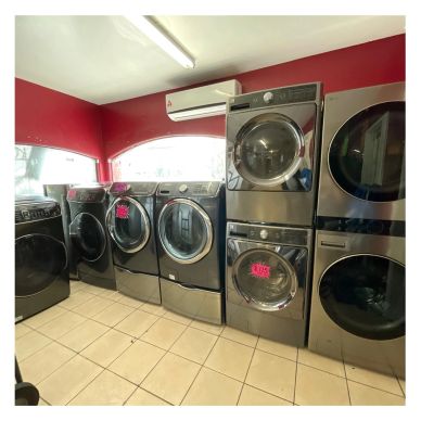Row of modern washing machines and dryers in a showroom.