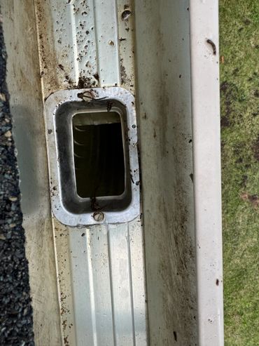 Dirty white metal surface with a rectangular opening and rusted screws.