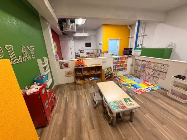 Colorful and organized preschool classroom with play area and learning materials.