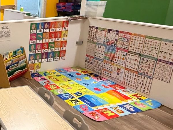 Colorful educational corner in a classroom with alphabet and number mats and posters.