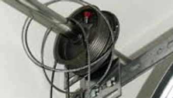 Close-up of a garage door torsion spring and winding bar setup.