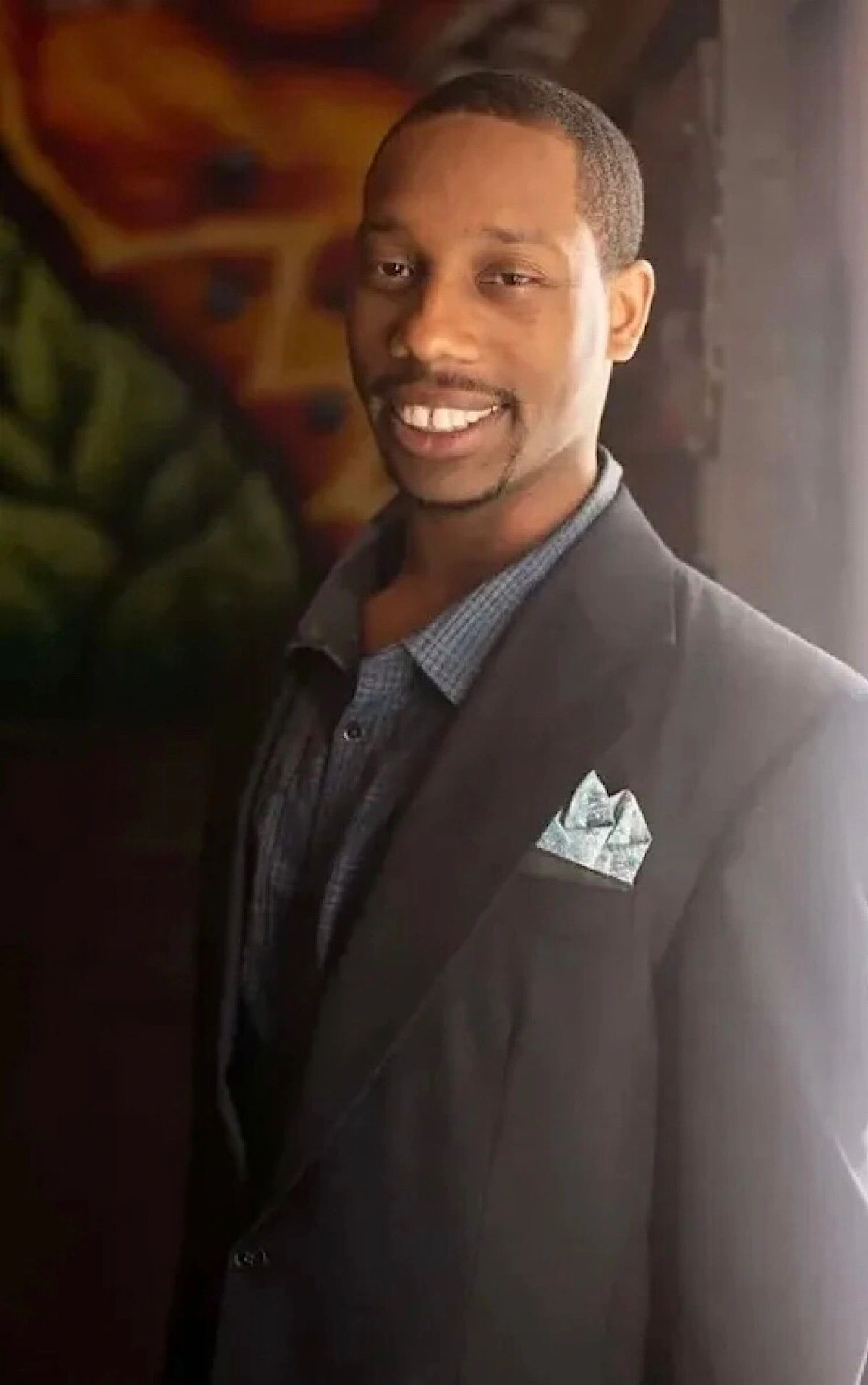 Smiling man in a dark suit with a pocket square.