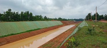 A long irrigation canal with green embankments and cloudy sky.