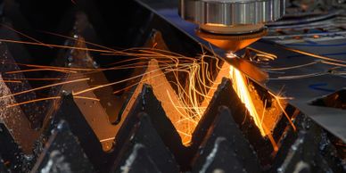 A CNC laser cutting metal with sparks flying.