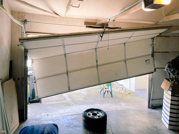 Partially open garage door with a tire on the floor inside the garage.