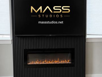 Black media wall with mounted TV and electric fireplace by MASS Studios.