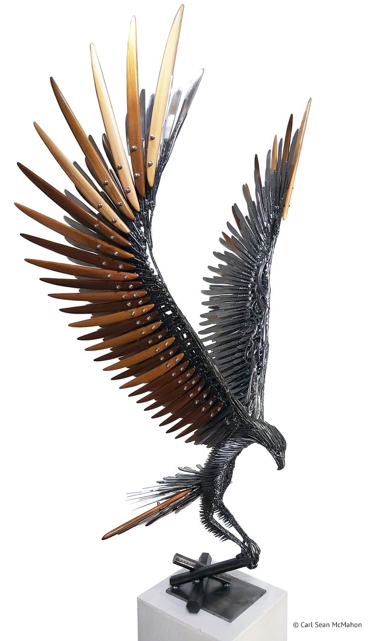 Front-right view of metal and cedar eagle sculpture with tiered wing colors on geometric base.