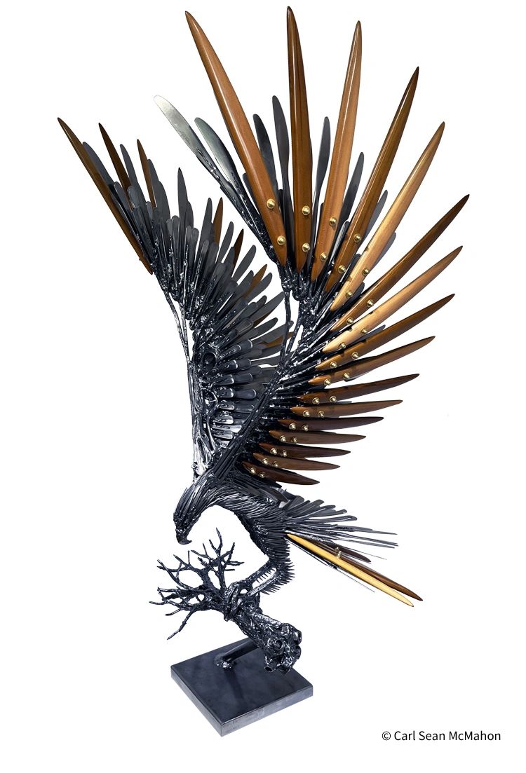 Front-left view of eagle sculpture in metal and cedar, perched on a reclaimed welded branch.
