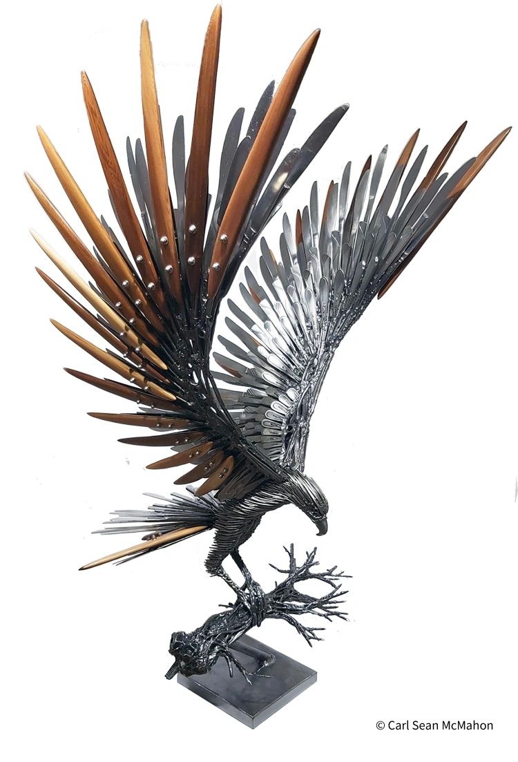 Eagle sculpture with cedar and cutlery feathers, front-right view perched on welded metal branch.