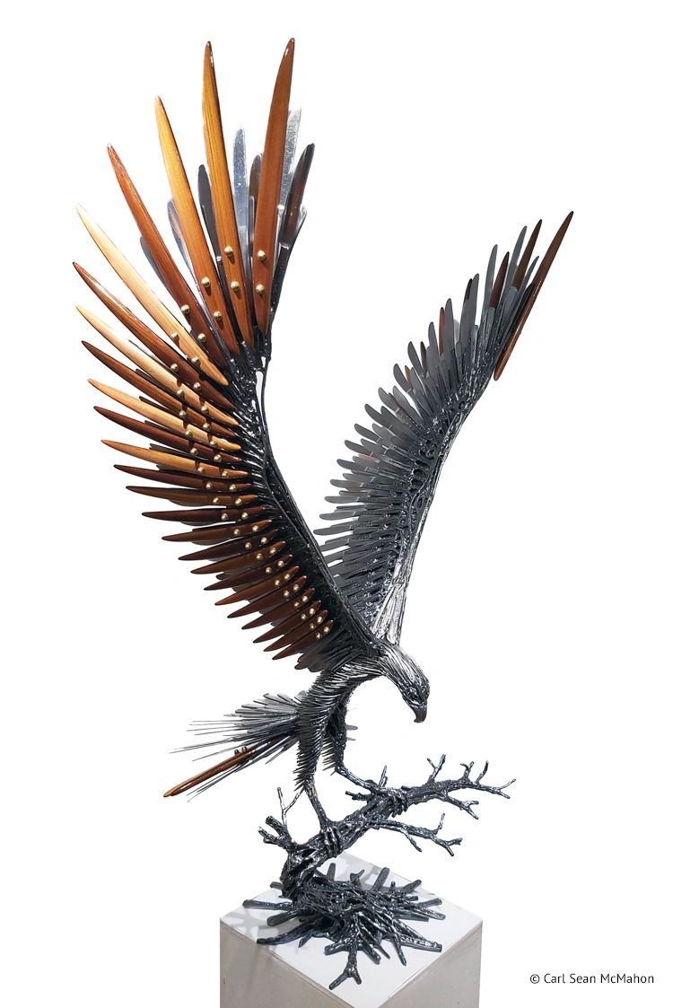 Smaller hawk sculpture in landing pose with cedar featherwork, shown from the front-right angle.