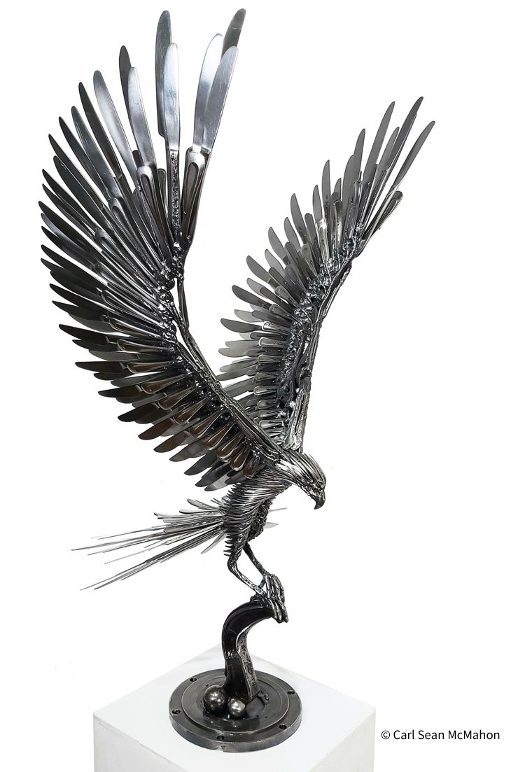 Front-right view of all-metal hawk sculpture with upward wings, perched on sculptural base.