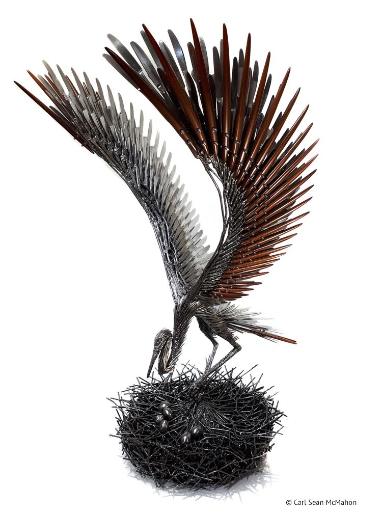 Indoor heron sculpture in metal and dark red cedar, front-left view with nest and visible eggs.