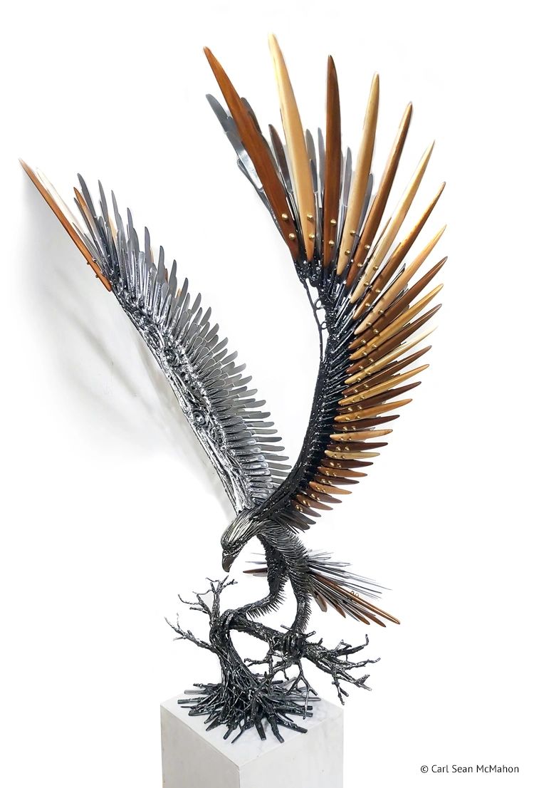 Large eagle sculpture in landing pose with cedar featherwork, shown from the front-left angle.