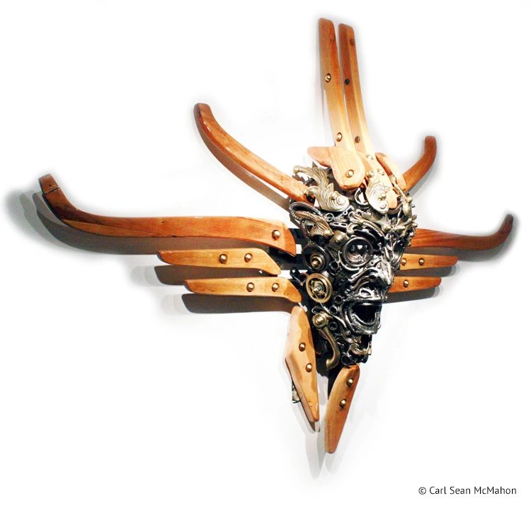 Angled view of Nexus II mask showing steel cross shape and brass highlights with pine components