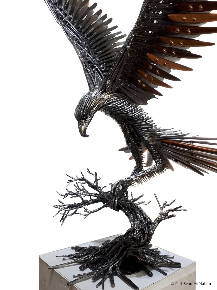 Close-up of eagle sculpture showing layered cedar feathers and reclaimed steel in head and chest.