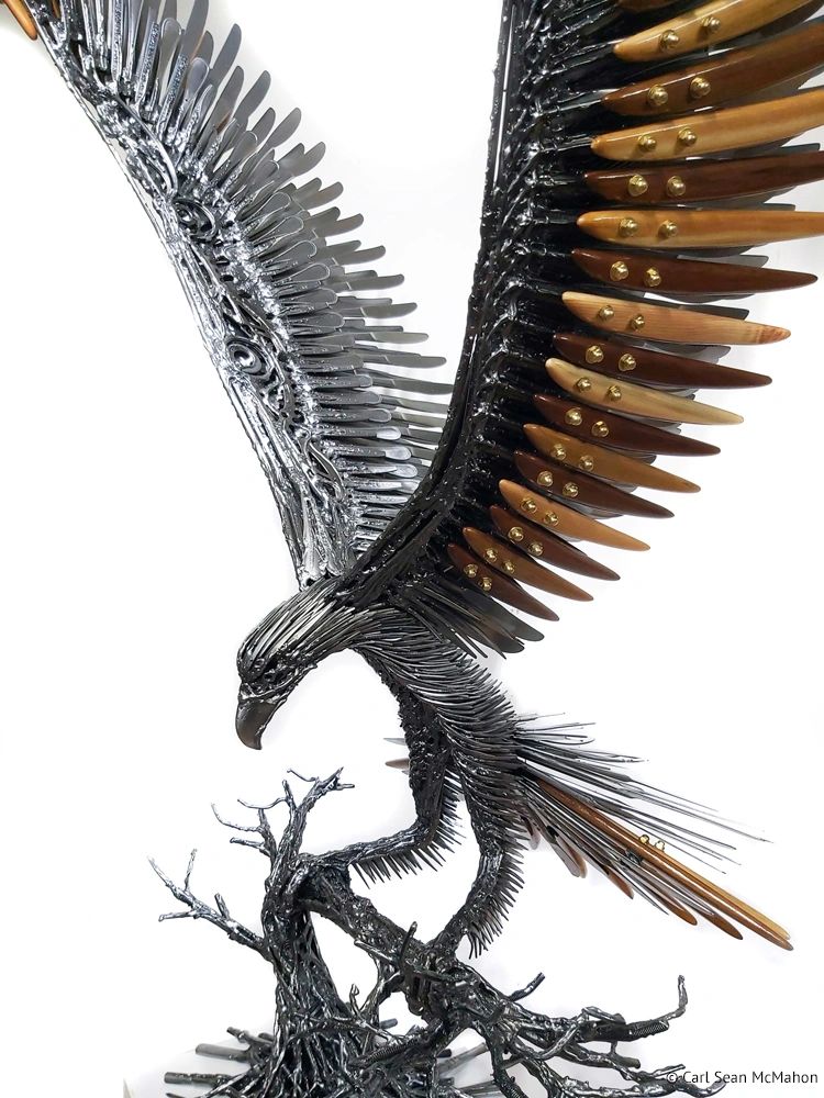 Close-up of metal and cedar featherwork on eagle sculpture showing texture and color transitions.