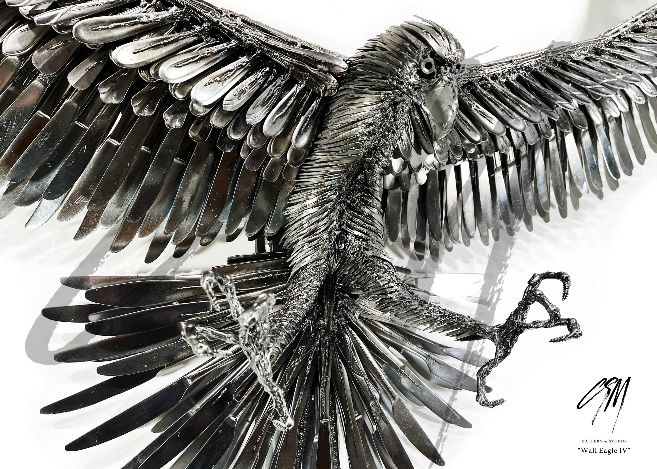 Close-up detail of eagle wing sculpture in reclaimed metal, showing refined form and texture.