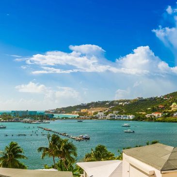Scenic view of a tropical bay with boats and lush hills under a blue sky.