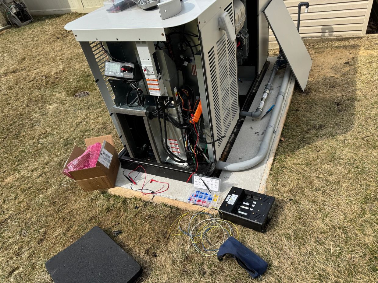 Outdoor HVAC unit with open panels and wiring tools scattered around.