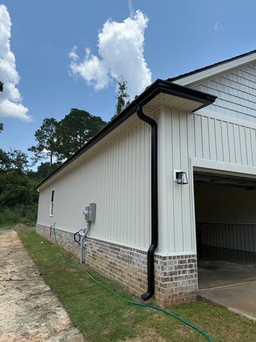 Side view of a modern garage with white siding and brick foundation under a blue sky.