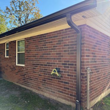 Brick house exterior with a downspout and bird feeder on a sunny day.