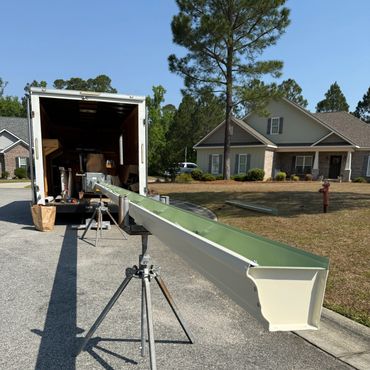 Gutter installation setup outside a house with tools and truck.