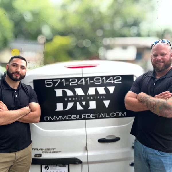DMV Mobile Detail owners standing next to their auto detailing vehicle with DMVmobiledetail.com sign