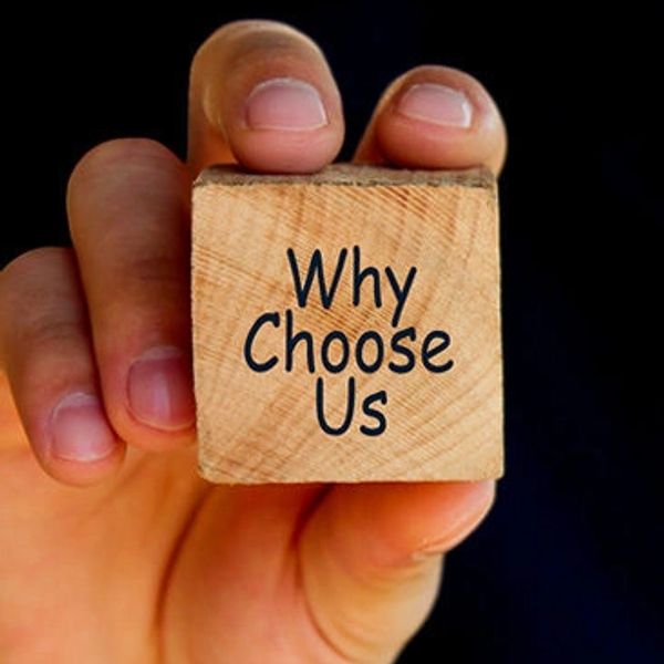 Upclose picture of a hand holding a wooden block that says “why choose us?” 